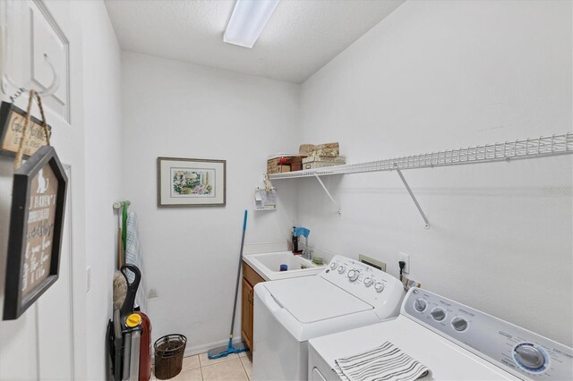 laundry room with cabinets, sink, light tile patterned floors, and washing machine and dryer