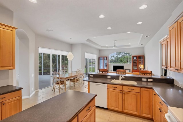 kitchen featuring hanging light fixtures, dishwasher, a tray ceiling, ceiling fan, and sink