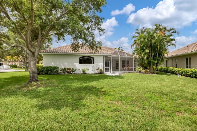 back of property featuring glass enclosure and a lawn