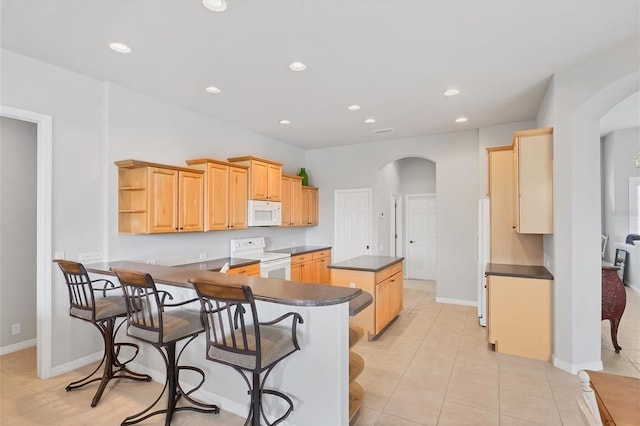 kitchen featuring light brown cabinets, light tile patterned flooring, kitchen peninsula, and white appliances