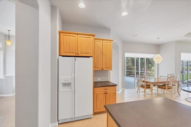 kitchen featuring a wealth of natural light, white fridge with ice dispenser, and decorative light fixtures