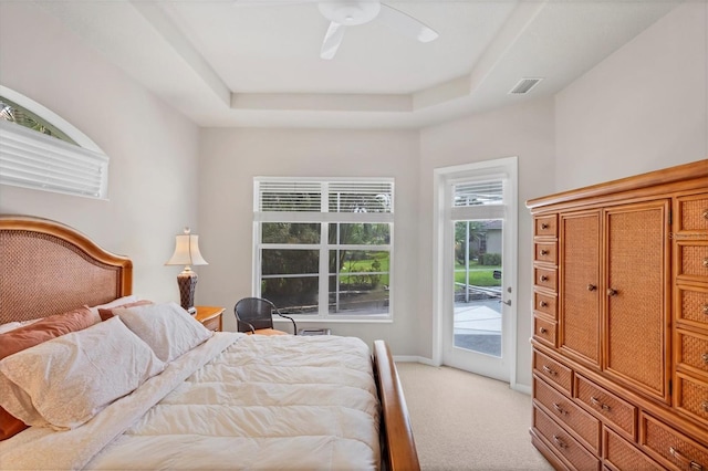 bedroom with light carpet, a tray ceiling, access to exterior, and ceiling fan