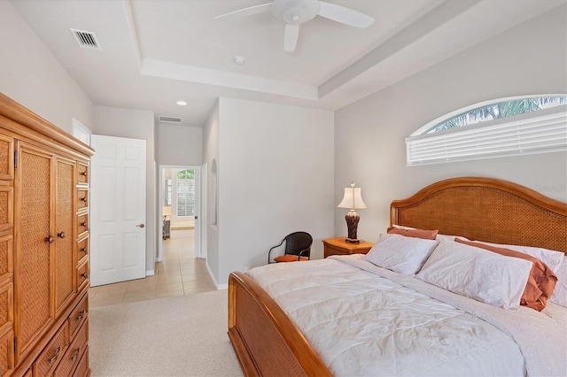 carpeted bedroom with a tray ceiling and ceiling fan