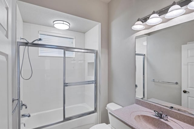 full bathroom with a textured ceiling, shower / bath combination with glass door, toilet, and vanity