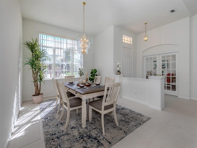 carpeted dining area with french doors and an inviting chandelier