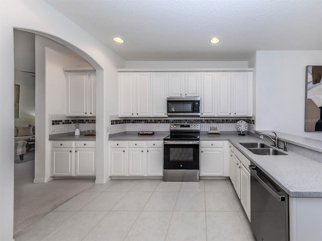 kitchen featuring backsplash, stainless steel appliances, sink, white cabinetry, and light tile patterned flooring