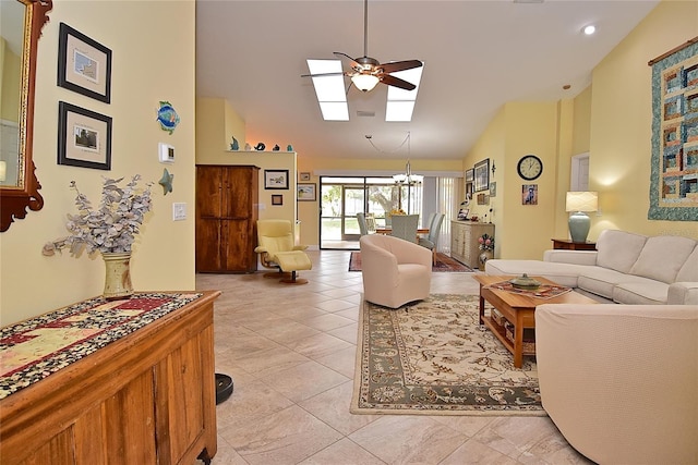 living room with a skylight, ceiling fan with notable chandelier, light tile patterned floors, and high vaulted ceiling