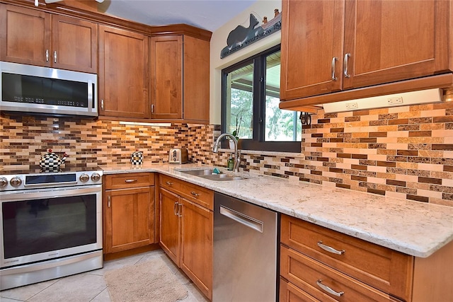 kitchen featuring sink, backsplash, appliances with stainless steel finishes, light tile patterned floors, and light stone countertops