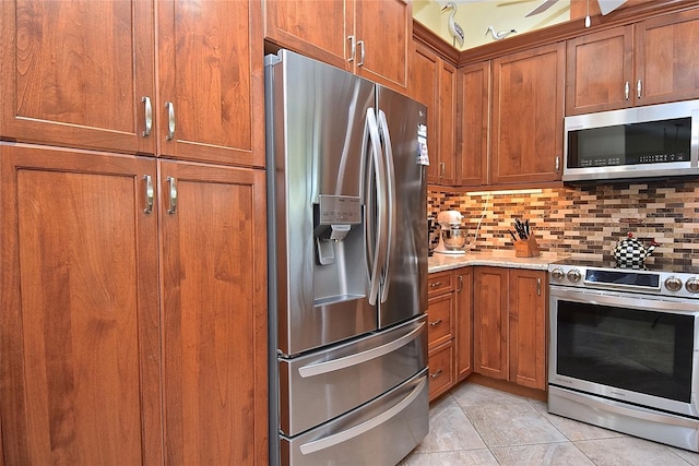 kitchen with light stone countertops, light tile patterned floors, appliances with stainless steel finishes, and tasteful backsplash