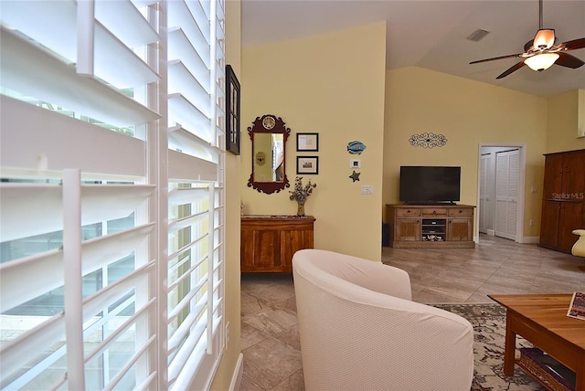 tiled living room with ceiling fan and high vaulted ceiling