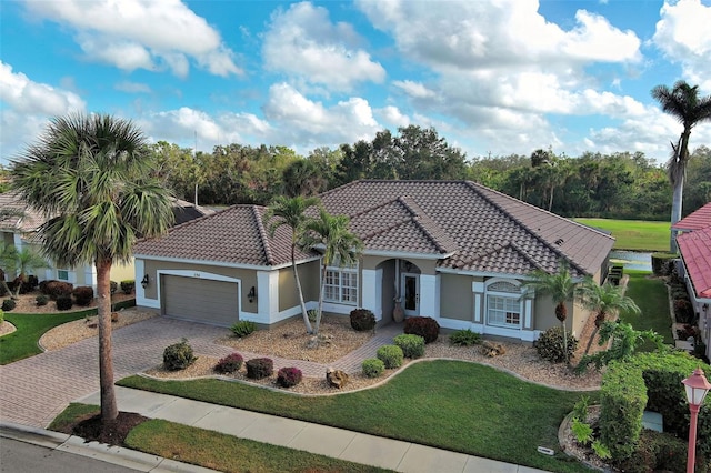 mediterranean / spanish house featuring a garage and a front yard