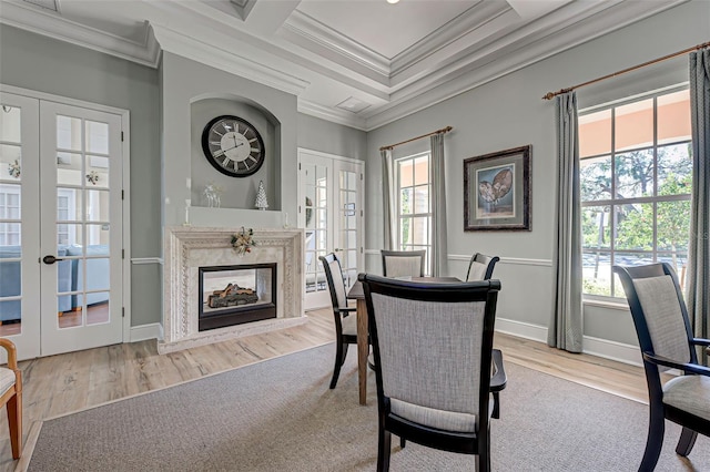 dining area featuring french doors, ornamental molding, a premium fireplace, and light hardwood / wood-style flooring