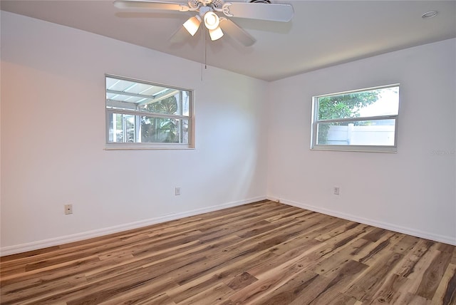 empty room featuring ceiling fan, hardwood / wood-style flooring, and a healthy amount of sunlight