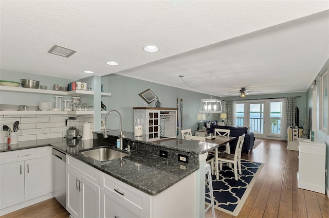 kitchen featuring sink, a textured ceiling, white cabinetry, dark hardwood / wood-style floors, and dark stone counters