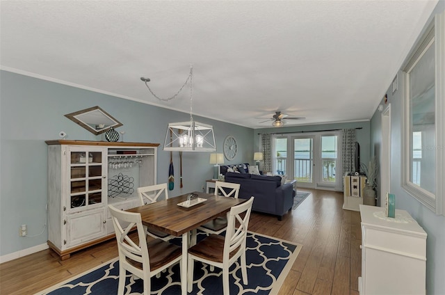 dining room featuring ornamental molding, a textured ceiling, ceiling fan with notable chandelier, and hardwood / wood-style floors