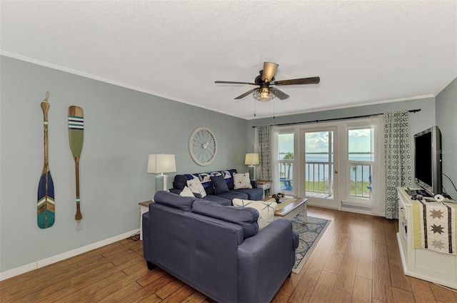 living room featuring wood-type flooring, ceiling fan, a textured ceiling, and crown molding