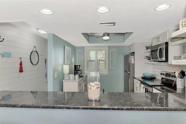 kitchen featuring dark stone countertops, white cabinets, a textured ceiling, and appliances with stainless steel finishes