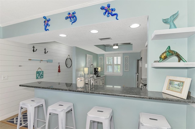 kitchen featuring a breakfast bar, kitchen peninsula, a textured ceiling, and hardwood / wood-style flooring