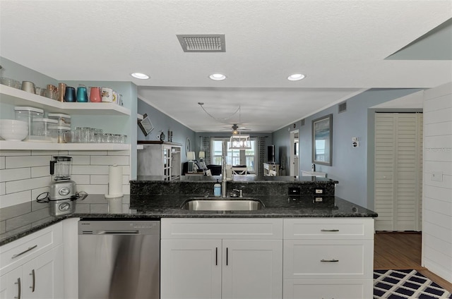 kitchen featuring dark stone countertops, dishwasher, sink, and white cabinets