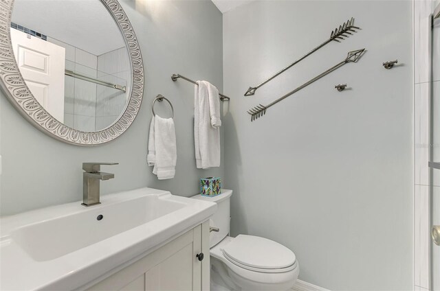 bathroom featuring a shower with door, toilet, and vanity