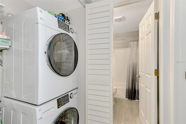 washroom featuring light hardwood / wood-style floors and stacked washing maching and dryer