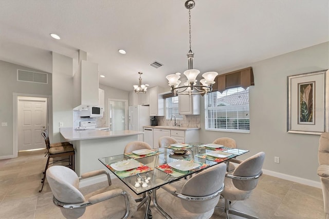 tiled dining space featuring a notable chandelier, sink, and lofted ceiling