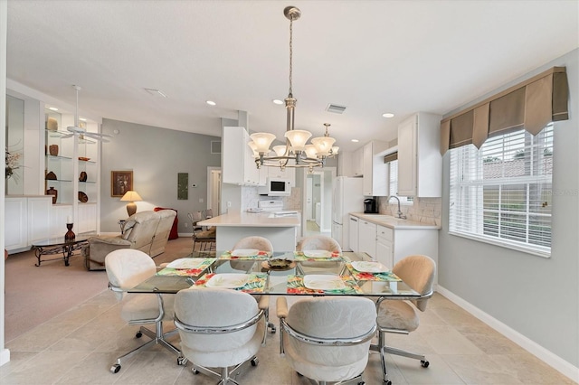 dining room featuring sink, light tile patterned flooring, and an inviting chandelier