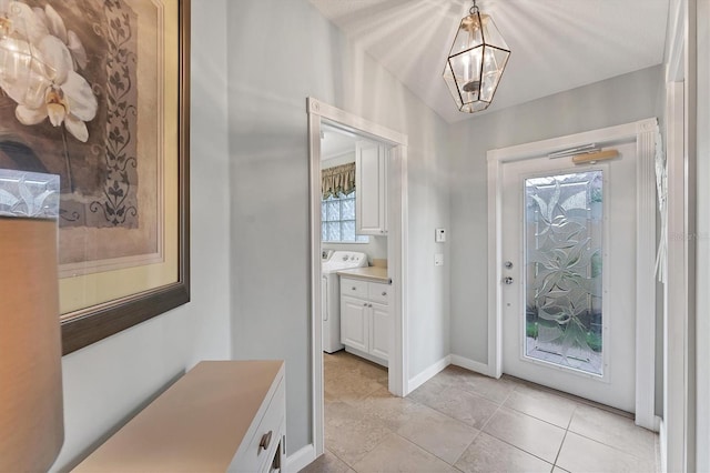 foyer with a notable chandelier, washer / clothes dryer, lofted ceiling, and light tile patterned flooring