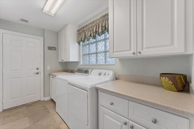 laundry area featuring sink, independent washer and dryer, a textured ceiling, and cabinets