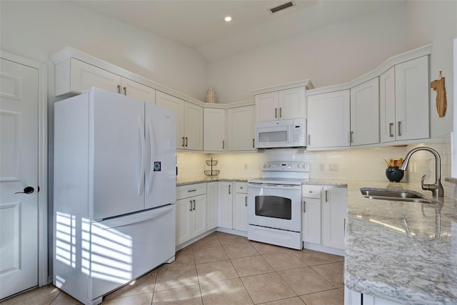 kitchen featuring white appliances, light stone counters, white cabinets, light tile patterned flooring, and sink