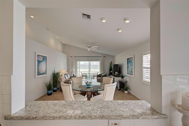 tiled dining space with ceiling fan, lofted ceiling, and a textured ceiling