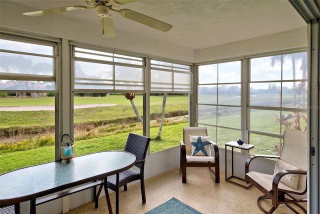 sunroom with ceiling fan and a rural view