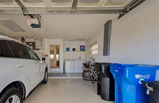 garage with electric panel, washing machine and clothes dryer, and a garage door opener