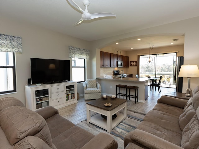 living room featuring sink, light hardwood / wood-style floors, and ceiling fan