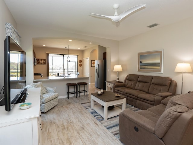 living room with ceiling fan and light hardwood / wood-style flooring