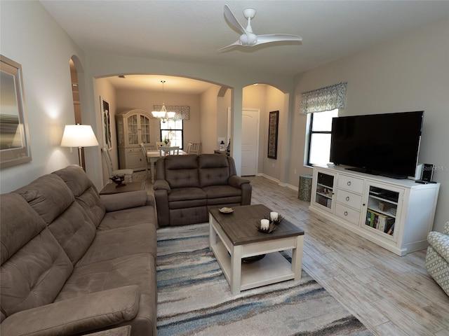 living room with light hardwood / wood-style floors, a healthy amount of sunlight, and ceiling fan with notable chandelier