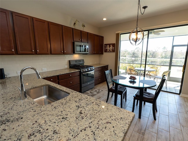 kitchen with sink, light stone counters, stainless steel appliances, and light wood-type flooring