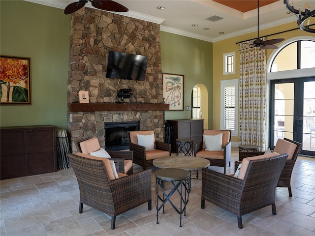 living room featuring a stone fireplace, crown molding, and ceiling fan