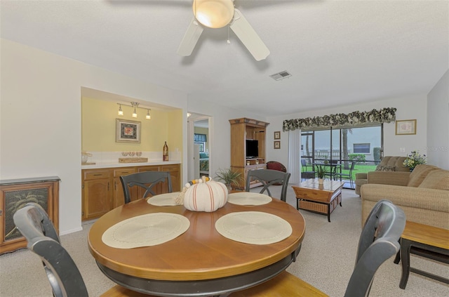 dining space featuring light colored carpet and ceiling fan