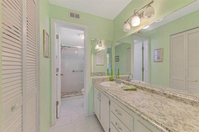 bathroom featuring toilet, vanity, tile patterned floors, and an enclosed shower