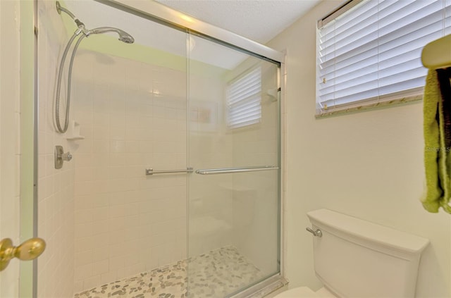 bathroom with a textured ceiling, toilet, and an enclosed shower