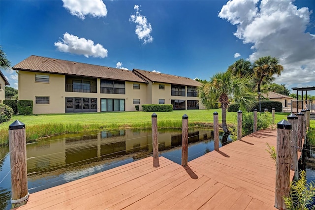 view of dock with a lawn and a water view