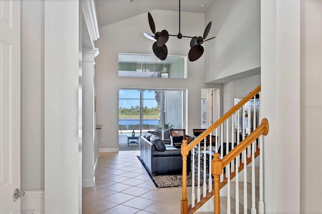 living room with ceiling fan, light tile patterned floors, a water view, and high vaulted ceiling