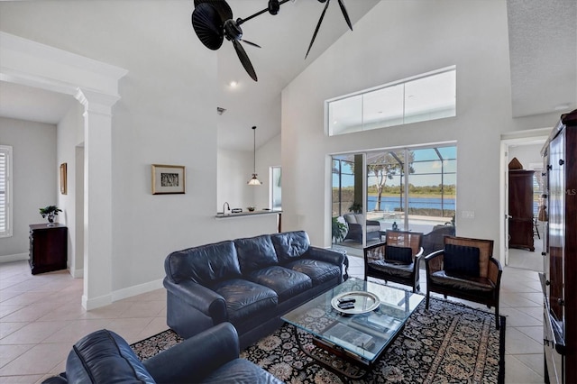 living room with ceiling fan, decorative columns, light tile patterned floors, and high vaulted ceiling