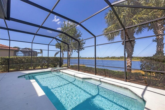 view of pool featuring an in ground hot tub, a patio, glass enclosure, and a water view