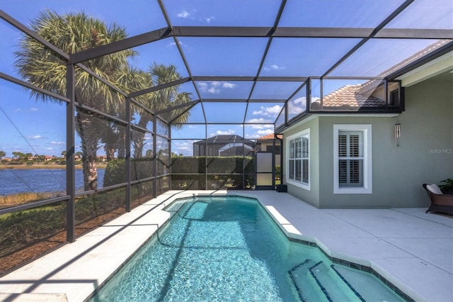 view of swimming pool featuring glass enclosure, a water view, and a patio area