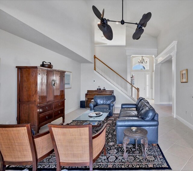 living room featuring an inviting chandelier, light tile patterned flooring, decorative columns, and high vaulted ceiling