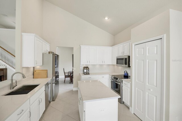 kitchen featuring white cabinets, sink, light stone counters, stainless steel appliances, and high vaulted ceiling