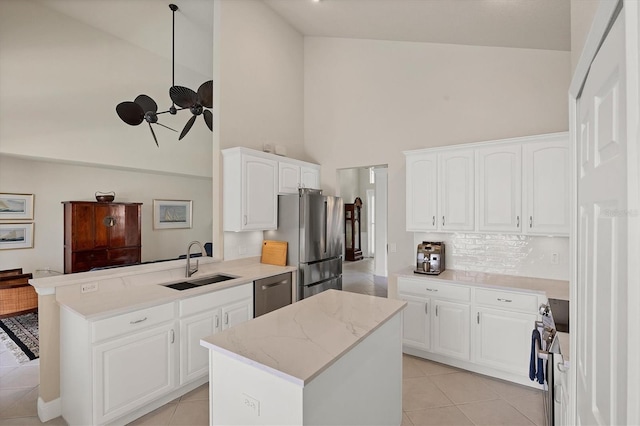 kitchen featuring sink, kitchen peninsula, high vaulted ceiling, appliances with stainless steel finishes, and white cabinetry