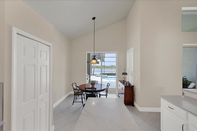 tiled dining room featuring high vaulted ceiling